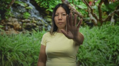 Geniş elli bir kadın ormanda jesti durdurur; kararlılık sınırı güvenliği.