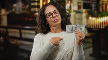 Kilisedeki kadın, Amerikan dolarlarını tutan, para ve maneviyatla ilgili duygularını kapalı bir ortamda aktaran..
