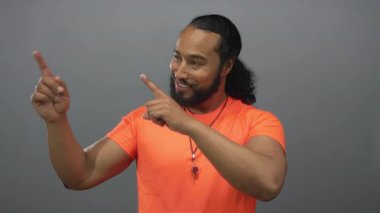 Stüdyoda her iki işaret parmağı ile anahtar halat ve çıplak kollar gösteren adam gri arkaplan ile; neşeli özgüven.