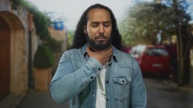 Boğulmak için boğazı sıkışan, gözleri kapalı, sokakta kot ceket giyen, tıbbi endişeleri olan bir adam..