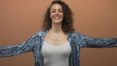 Şeftali atölyesinde gülümseyen bir kadın desenli gömlek ve beyaz tanktop giyerek göğsünü işaret ediyor..