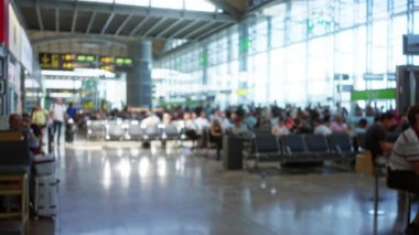 Yoğun bir istasyonda yumuşak bokeh, sıra sıra koltuklar ve camlı pencerelerle bulanık havaalanı içi; arkaplan telif alanı arka planı.