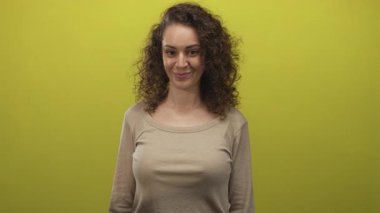 İşaret parmağıyla kamerayı işaret eden kadın yüz yüze ve limon yeşili stüdyoda hafif bir sırıtış..