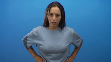 İspanyol kadın bir eliyle mavi bir stüdyo arkaplanını işaret ediyor..