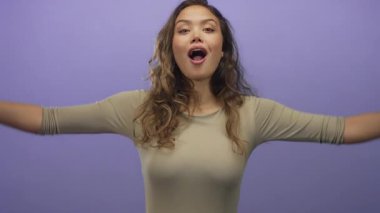 Genç İspanyol kadın, izole edilmiş parlak mor stüdyoda el kaldırarak çatı şekli oluşturur..
