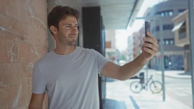 Şehir caddesinde bisiklet parkına yakın bir yerde akıllı telefondan selfie çeken adam, şehir bağlantısı güveni.