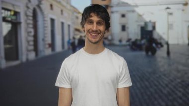 Beyaz tişörtlü genç adam sabah güneş ışığı altında dişlerini gösteren gülümsemeler; iyimserlik güveni neşe.