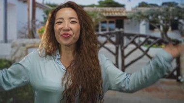 Uzun saçlı genç kadın ahşap kapı ve saksı bitkisinin girişinde elleri ve elleri ile gözleri örten neşeli sürpriz.