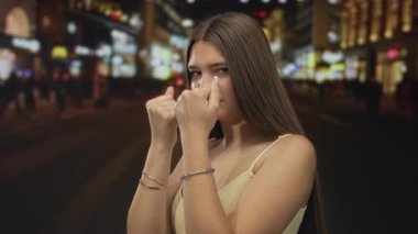 Gece vakti kalabalık bir neon ışıklı şehir caddesinde boks gardı içinde büyüyen yumruklu genç bir kadın..