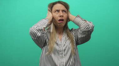 Çizgili tişörtlü sarışın kadın kulaklarını kulaklarıyla kapatıyor..