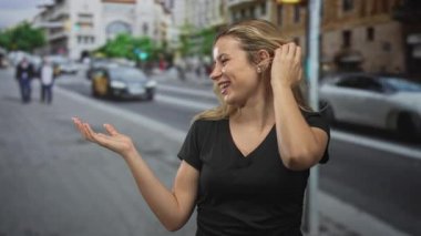 Avuç içi açık jestli ve eli kalçasında bir kadın sokakta bulanık arabaların ve yayaların arasında gülümsüyor; mutluluk tasasız.