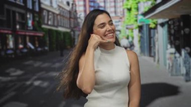 Kentsel sokak sahnesinde kadın omuz ve kol, arkasında binalar bulunan yüz yüze çağrı jesti gösteriyor; sevinç.