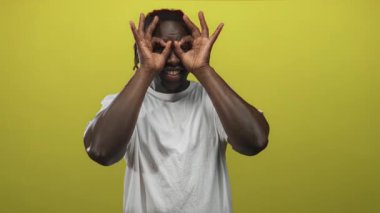 Erkekler el dürbünü hareketlerini görünür eller ve stüdyoda sarı arka planda geniş bir gülümseme ile yaparlar; neşeli oyun.