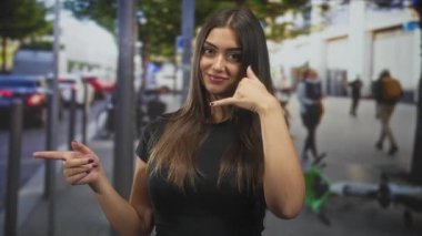 Sol parmakla işaret eden ve el kulağına konuşan, elektrikli scooter 'ın yanında el kol hareketi yapan ve sokakta yayaları bulanıklaştıran bir kadın..