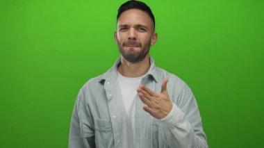 Hispanik genç adam canlı yeşil arka plana karşı elleri göğsünde duygularını ifade ediyor.
