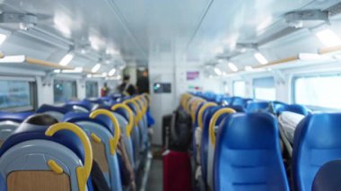 Yumuşak bokeh koltukları, koridor ve tepedeki ışıklandırması serin tonlara odaklanmış bir banliyö treninin bulanık ve sığ iç mekanı; arka plan telif alanı şablonu.