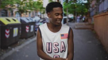 Şehir caddesinde çöp ve geri dönüşüm konteynırlarını işaret eden adam; çevresel sorumluluk belirleme.