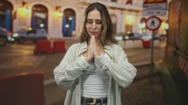 Gözleri kapalı dua eden bir kadın ve arabaların yanındaki kalabalık bir sokakta meditasyon yapan bir mudra ve yaya tabelası olan bir kadın..