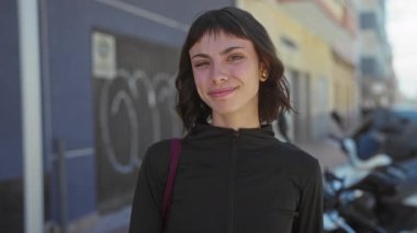 Güneşli şehir sokağında park etmiş scooter 'ın yanında gülümseyen yüzü olan kadın. Mutluluk..