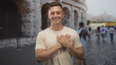 Kalabalık bir caddede kolezyumun önünde elleri göğsünde gülümseyen genç adam şükran yolculuğu hafızası..