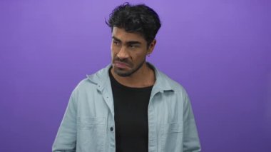 Mor bir stüdyoda, açık mavi kot gömlekli genç adam el ele tutuşup genişliğini ölçüyor..