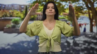 Sabahın erken saatlerinde kalabalık bir yaya caddesinde sakin bir jest yapmak için iki elini de havaya kaldıran kadın..