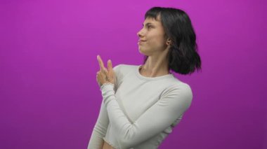 Stüdyoda beyaz bluz giyen, yüzünde sırıtış olan dövmeli elleri gösteren bir kadın. Kararsızlık..