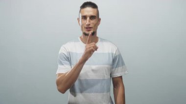 Stüdyoda açık mavi ve beyaz çizgili bir tişört ve görünür bir ön kol giyerek sessiz sedasız konuşma yapan parmaklı bir adam..