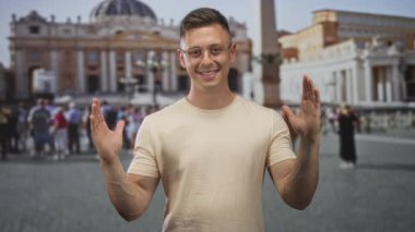 Kalabalık bir meydanda tarihi bir binanın önünde el kaldıran ve avuçlarını açık tutan bir adam..