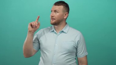 Adam işaret parmağı yukarı doğru işaret ediyor, çıplak el ve rahat gülümseme ile köşeden yukarı bakarken; fikir iyimserliği.