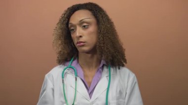 Beyaz önlüklü, yeşil steteskoplu İspanyol transseksüel doktor şeftali atölyesinde gözlük ayarlıyor..