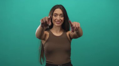 Genç İspanyol kadın iki parmağını da kameraya çekiyor. Stüdyonun deniz mavisi zemininde elleri görünüyor. Güven bağlantısı:.