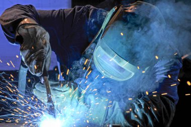 Endüstri - yüz kalkanı, tulum ve eldivenlerle kaynakçı iş başında
