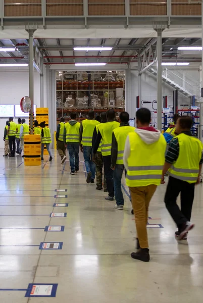 Worker with yellow jacket moving as a team in a delivery warehouse