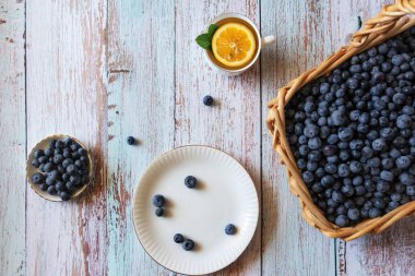 Taze yaban mersini, limonlu çay ve ahşap masa arkasında nane.