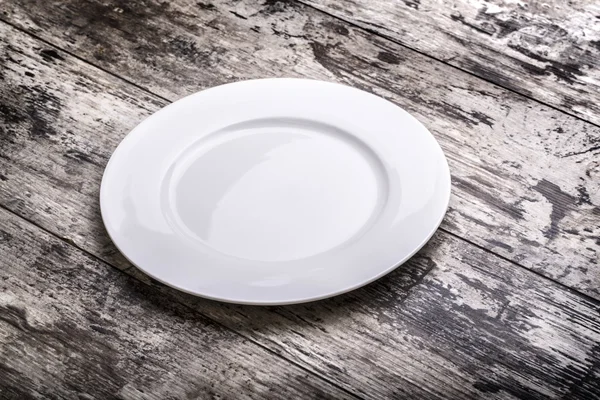 Белая тарелка на столе — стоковое фото