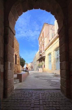 Chania, Yunanistan, 11 Kasım 2025: Taş kemer, tarihi caddeleri binalarla donatıyor ve bir kişi dinleniyor