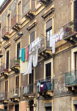 Geleneksel bir Avrupa binası cephesinin balkonları arasında çamaşırhaneler asılı.