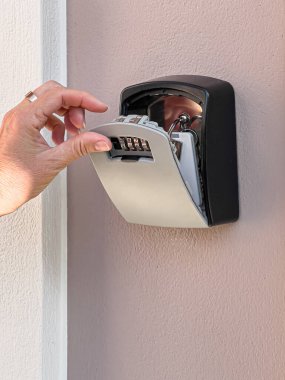 Elle monte edilmiş bir anahtar kasasını açmak, içerideki evin anahtarlarını açığa çıkarmak için.