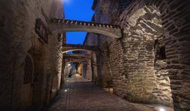 Günbatımında Avrupa 'nın bir şehrinde tarihi taş kemerlerin ve aydınlık duvarların yer aldığı ortaçağ kaldırım taşından bir sokak.