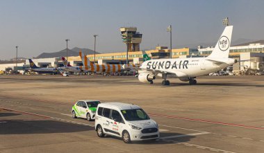 Sundair uçağı pistte hareket ediyor. Terminal ve kontrol kulesi de arkada.