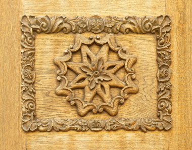 Dekoratif çiçek elementleriyle çevrili merkezi bir yıldızın yer aldığı karmaşık el oyması ahşap panel.