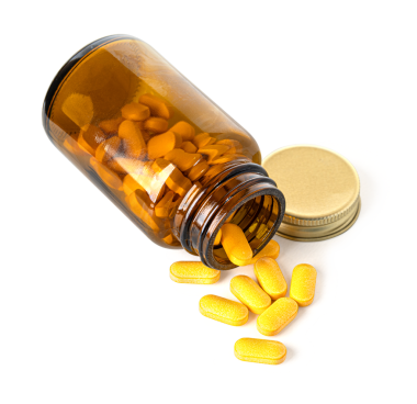 Kehribar cam şişeden altın kapaklı turuncu haplar dökülüyor.