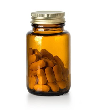 Beyaz arka planda turuncu ilaç tabletleriyle dolu kehribar cam şişe.