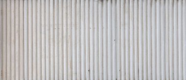 Beyaz kıvrımlı metal panel yinelenen bir dikey doku kalıbı oluşturuyor