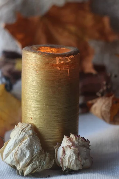 Hohe goldene Kerze mit getrockneten Blumen an der Basis und Herbst Hintergrund — Stockfoto