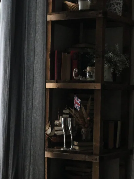 Armario con libros, vasos y decoración junto a la ventana — Foto de Stock