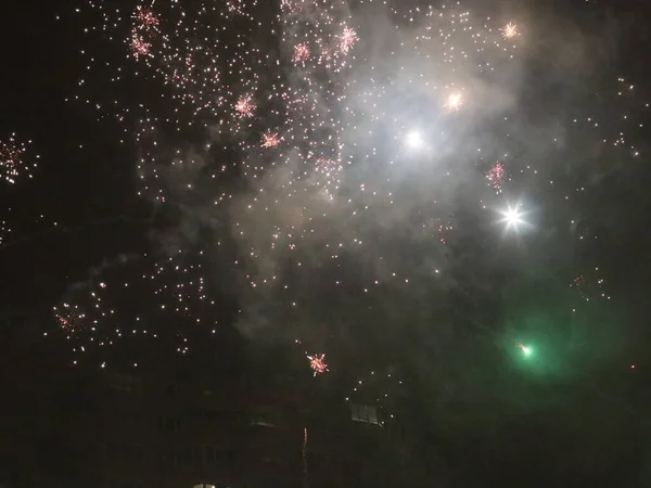 Fuegos artificiales multicolores de año nuevo en el cielo oscuro —  Fotos de Stock