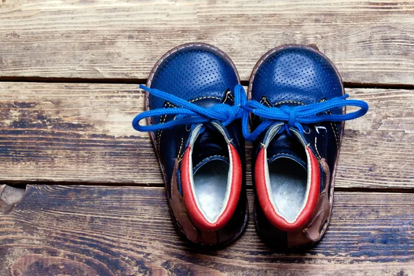 Buty dla dzieci na drewnianej podłodze. — Zdjęcie stockowe