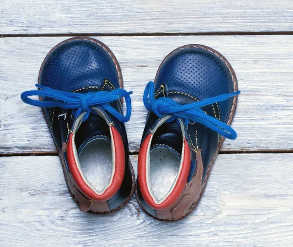 Buty dla dzieci na drewnianej podłodze. — Zdjęcie stockowe